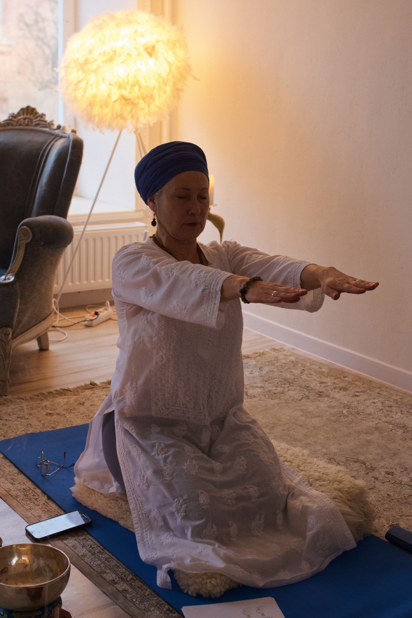 Linda wearing a blue turban practising yoga with her arms extended