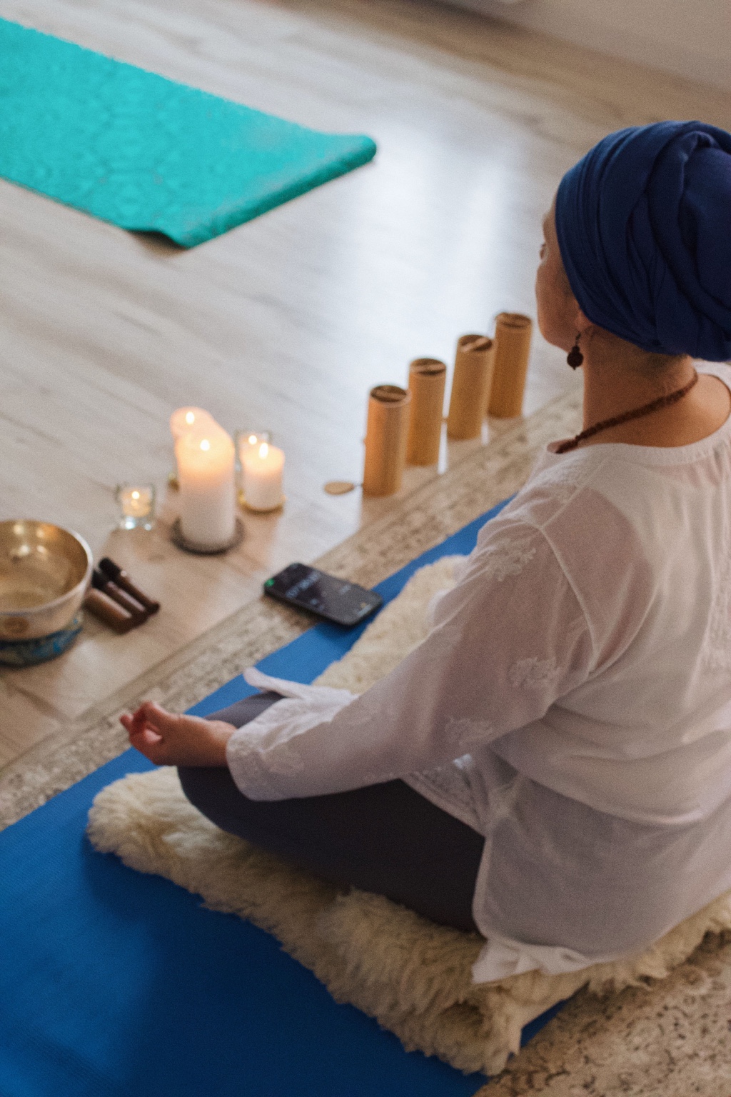 Linda wearing a blue turban meditating beside candles