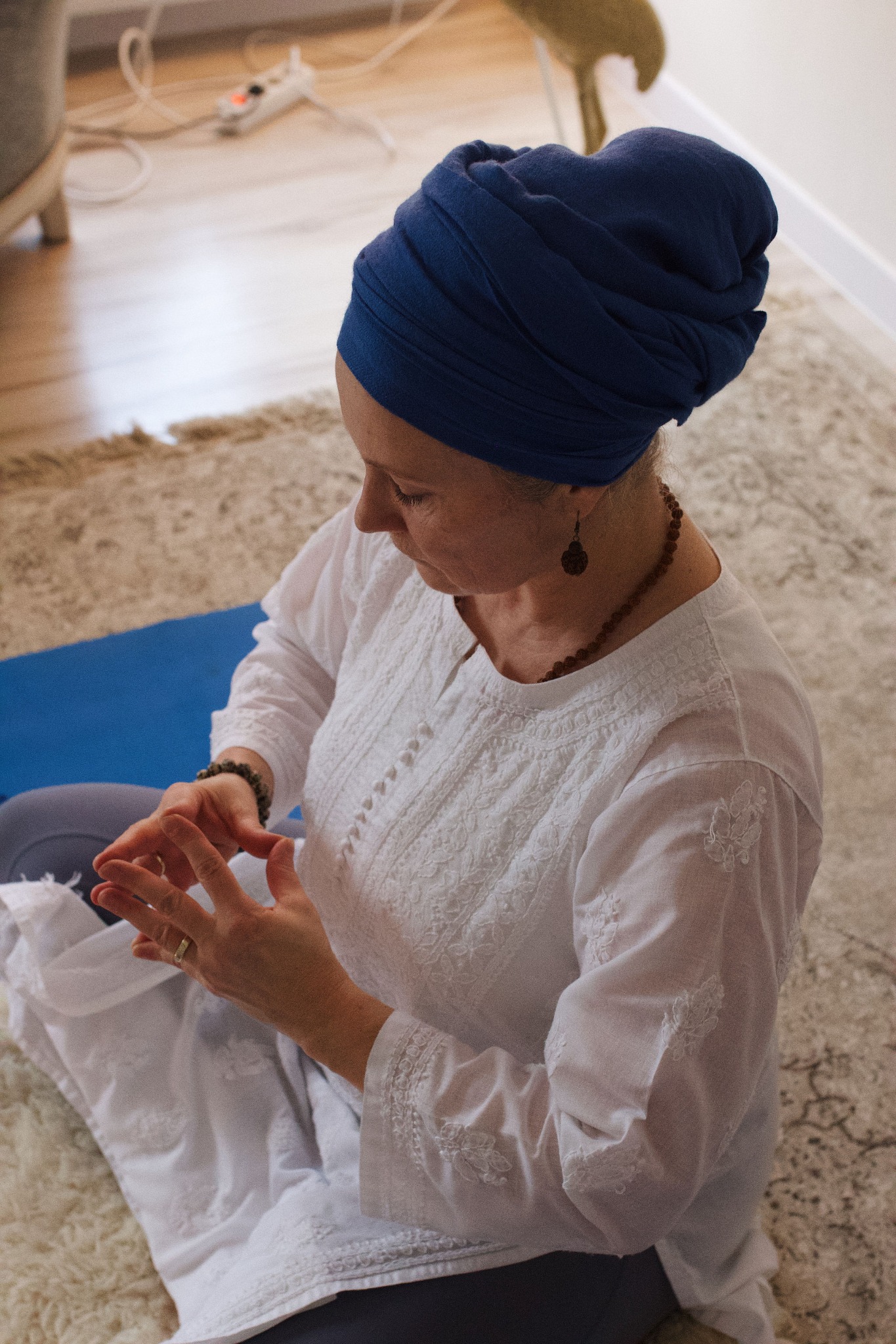 Linda wearing a blue turban meditating with a hand mudra